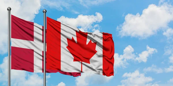 Dánsko a Kanada vlajkami vlnící se ve větru proti bíle zatažené modré obloze. Diplomacie, mezinárodní vztahy. — Stock fotografie