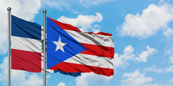 Η Δομινικανή Δημοκρατία και η σημαία του Πουέρτο Ρίκο χαιρετούν τον άνεμο ενάντια στο λευκό συννεφιασμένο γαλάζιο του ουρανού μαζί. Φιλοσοφία της διπλωματίας, διεθνείς σχέσεις. — Φωτογραφία Αρχείου