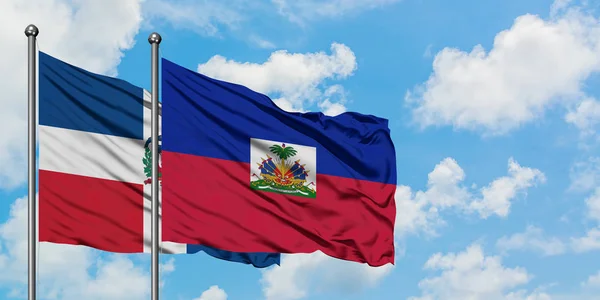 Dominicaanse Republiek en Haïti vlag zwaaien in de wind tegen witte bewolkte blauwe hemel samen. Diplomatie concept, internationale betrekkingen. — Stockfoto