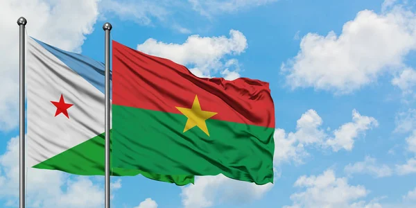 Bandera de Djibouti y Burkina Faso ondeando en el viento contra el cielo azul nublado blanco juntos. Concepto diplomático, relaciones internacionales . — Foto de Stock