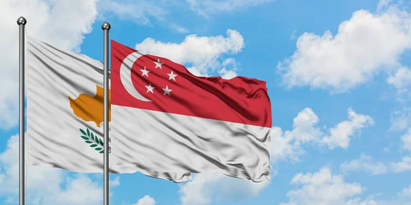 Zypern und die Singapore-Flagge wehen gemeinsam im Wind gegen den wolkenverhangenen blauen Himmel. Diplomatie-Konzept, internationale Beziehungen. — Stockfoto