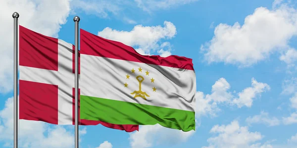 Bandera de Dinamarca y Tayikistán ondeando en el viento contra el cielo azul nublado blanco juntos. Concepto diplomático, relaciones internacionales . — Foto de Stock