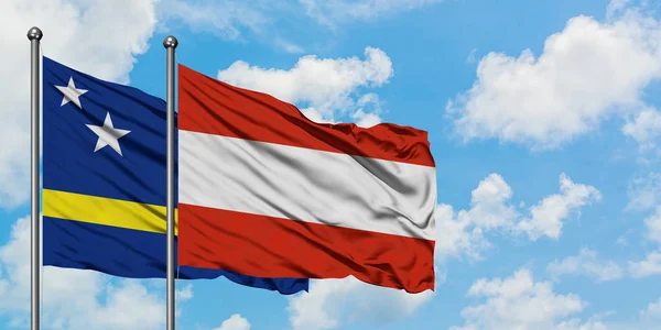 Curaçao e a bandeira da Áustria agitando no vento contra o céu azul nublado branco juntos. Conceito de diplomacia, relações internacionais . — Fotografia de Stock