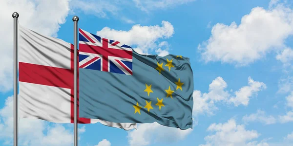 Bandera de Inglaterra y Tuvalu ondeando en el viento contra el cielo azul nublado blanco juntos. Concepto diplomático, relaciones internacionales . — Foto de Stock