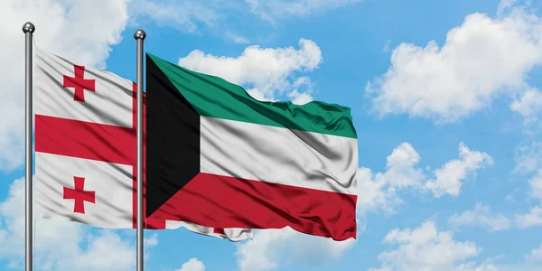 Bandera de Georgia y Kuwait ondeando en el viento contra el cielo azul nublado blanco juntos. Concepto diplomático, relaciones internacionales . — Foto de Stock