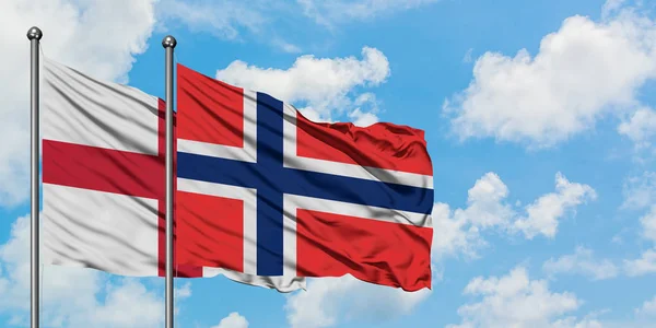 Bandera de Inglaterra y Bouvet Islands ondeando en el viento contra el cielo azul nublado blanco juntos. Concepto diplomático, relaciones internacionales . — Foto de Stock