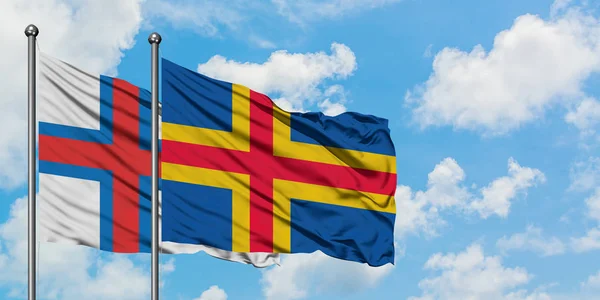 Wyspy Owcze i Wyspy Alandzkie flagi machając w wiatr przed białym pochmurno błękitne niebo razem. Koncepcja dyplomacji, stosunki międzynarodowe. — Zdjęcie stockowe