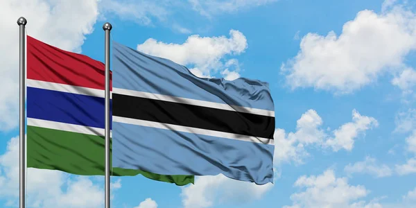 Gambia e Botswana sventolano nel vento contro il bianco cielo azzurro nuvoloso insieme. Concetto di diplomazia, relazioni internazionali . — Foto Stock