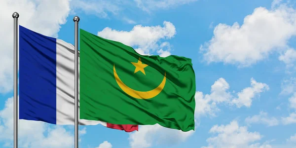 Bandera de Francia y Mauritania ondeando en el viento contra el cielo azul nublado blanco juntos. Concepto diplomático, relaciones internacionales . — Foto de Stock