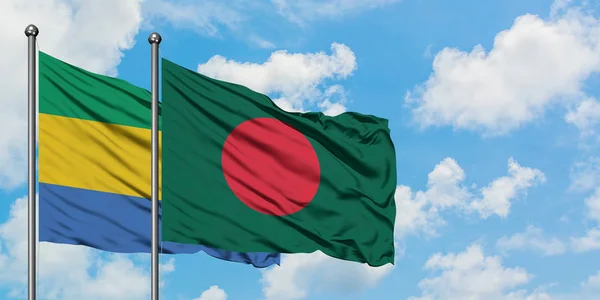 Bandera de Gabón y Bangladesh ondeando en el viento contra el cielo azul nublado blanco juntos. Concepto diplomático, relaciones internacionales . — Foto de Stock