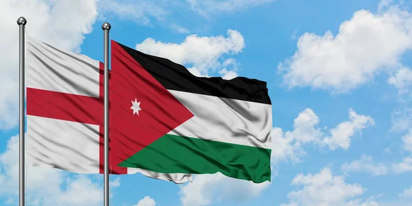 Bandera de Inglaterra y Jordania ondeando en el viento contra el cielo azul nublado blanco juntos. Concepto diplomático, relaciones internacionales . — Foto de Stock
