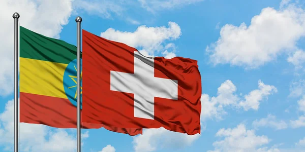 Etiopía y Suiza bandera ondeando en el viento contra el cielo azul nublado blanco juntos. Concepto diplomático, relaciones internacionales . — Foto de Stock