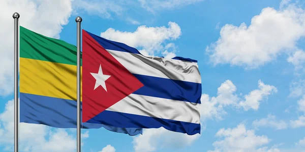 Gabão e Cuba acenando ao vento contra o céu azul nublado branco juntos. Conceito de diplomacia, relações internacionais . — Fotografia de Stock