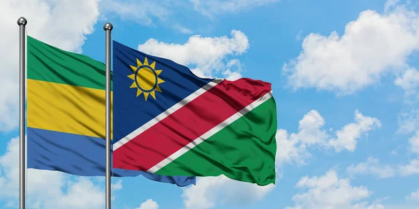 Gabon és Namíbia zászló integetett a szél ellen, fehér felhős kék ég együtt. Diplomáciai koncepció, nemzetközi kapcsolatok. — Stock Fotó