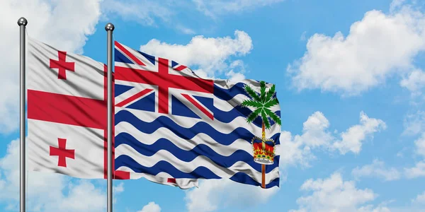 格鲁吉亚和英属印度洋领土国旗在风中飘扬，白云蓝天相聚。外交概念、国际关系. — 图库照片