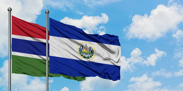 Bandera de Gambia y El Salvador ondeando en el viento contra el cielo azul nublado blanco juntos. Concepto diplomático, relaciones internacionales . — Foto de Stock