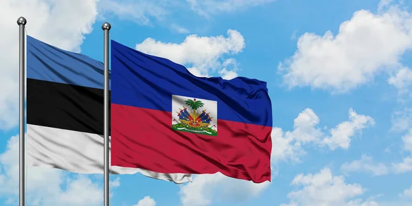 Estonya ve Haiti bayrağı birlikte beyaz bulutlu mavi gökyüzüne karşı rüzgarda sallayarak. Diplomasi kavramı, uluslararası ilişkiler. — Stok fotoğraf