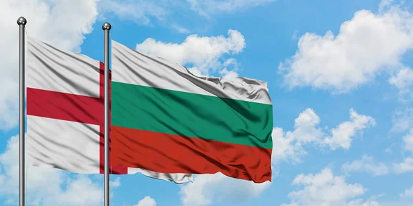 Bandera de Inglaterra y Bulgaria ondeando en el viento contra el cielo azul nublado blanco juntos. Concepto diplomático, relaciones internacionales . — Foto de Stock