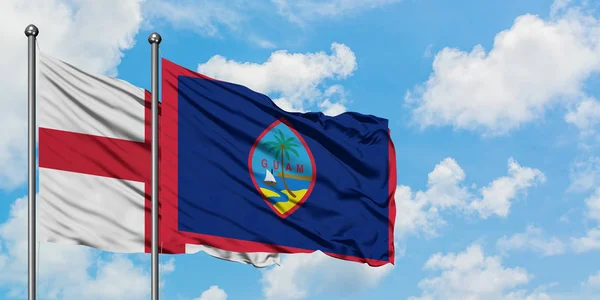 Bandera de Inglaterra y Guam ondeando en el viento contra el cielo azul nublado blanco juntos. Concepto diplomático, relaciones internacionales . — Foto de Stock