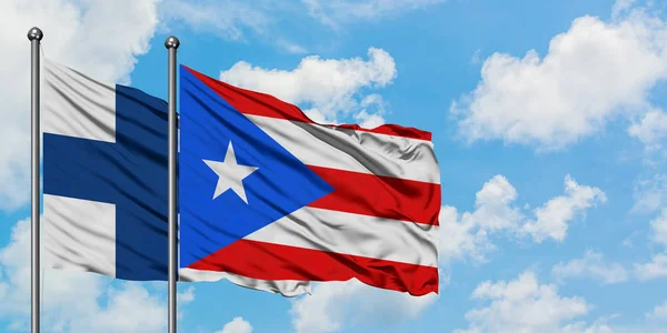 Finlandiya ve Porto Riko bayrağı birlikte beyaz bulutlu mavi gökyüzüne karşı rüzgarda sallayarak. Diplomasi kavramı, uluslararası ilişkiler. — Stok fotoğraf