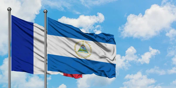 Francie a Nikaragujská vlajka mávali větrem proti bílé zatažené modré obloze. Diplomacie, mezinárodní vztahy. — Stock fotografie