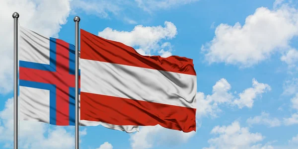 Bandera de las Islas Feroe y Austria ondeando en el viento contra el cielo azul nublado blanco juntos. Concepto diplomático, relaciones internacionales . — Foto de Stock