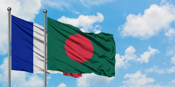 Bandera de Francia y Bangladesh ondeando en el viento contra el cielo azul nublado blanco juntos. Concepto diplomático, relaciones internacionales . — Foto de Stock