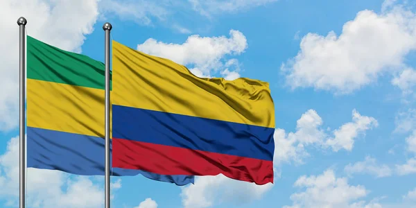 Bandera de Gabón y Colombia ondeando en el viento contra el cielo azul nublado blanco juntos. Concepto diplomático, relaciones internacionales . — Foto de Stock