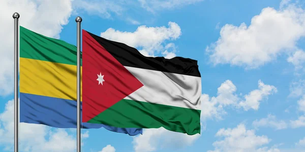 Gabon and Jordan flag waving in the wind against white cloudy blue sky together. Diplomacy concept, international relations.