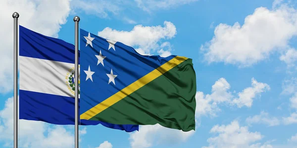 El Salvador and Solomon Islands flag waving in the wind against white cloudy blue sky together. Diplomacy concept, international relations. — Stock Photo, Image