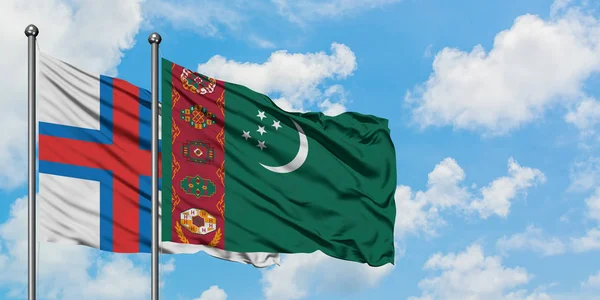 Bandera de las Islas Feroe y Turkmenistán ondeando en el viento contra el cielo azul nublado blanco juntos. Concepto diplomático, relaciones internacionales . — Foto de Stock