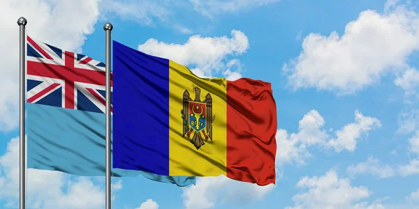 Bandera de Fiyi y Moldavia ondeando en el viento contra el cielo azul nublado blanco juntos. Concepto diplomático, relaciones internacionales . — Foto de Stock