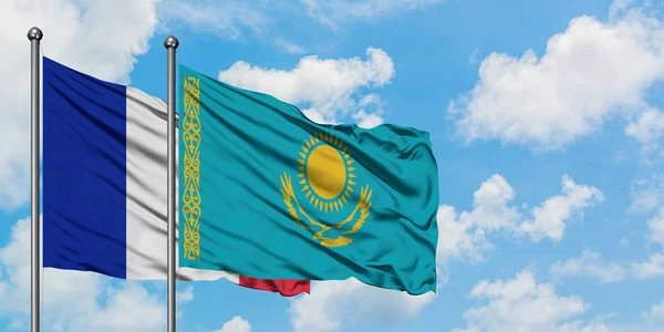 Bandera de Francia y Kazajstán ondeando en el viento contra el cielo azul nublado blanco juntos. Concepto diplomático, relaciones internacionales . — Foto de Stock