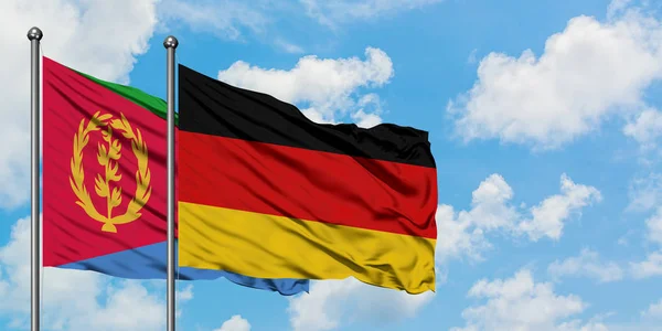 Bandera de Eritrea y Alemania ondeando en el viento contra el cielo azul nublado blanco juntos. Concepto diplomático, relaciones internacionales . — Foto de Stock