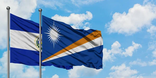 El Salvador and Marshall Islands flag waving in the wind against white cloudy blue sky together. Diplomacy concept, international relations. — Stock Photo, Image