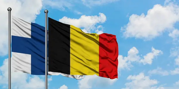 芬兰和比利时国旗在风中飘扬，与白云蓝天相一起。外交概念、国际关系. — 图库照片