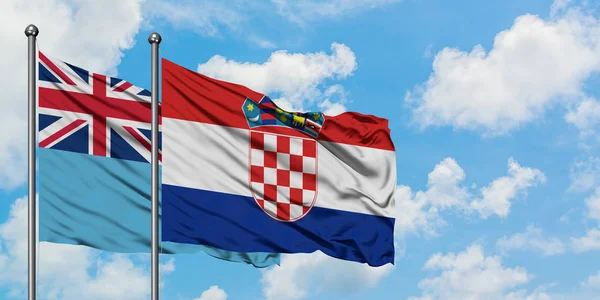 Bandera de Fiyi y Croacia ondeando en el viento contra el cielo azul nublado blanco juntos. Concepto diplomático, relaciones internacionales . — Foto de Stock