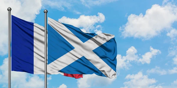 France and Scotland flag waving in the wind against white cloudy blue sky together. Diplomacy concept, international relations.