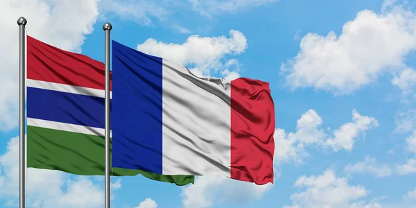 Gambia e la Francia bandiera sventolando nel vento contro bianco cielo blu nuvoloso insieme. Concetto di diplomazia, relazioni internazionali . — Foto Stock