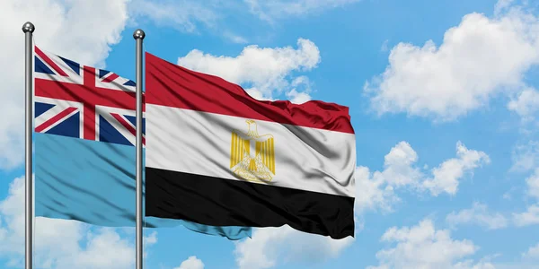 Bandera de Fiji y Egipto ondeando en el viento contra el cielo azul nublado blanco juntos. Concepto diplomático, relaciones internacionales . — Foto de Stock