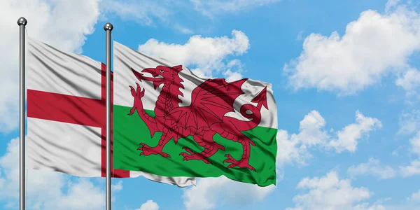 一緒に白い曇り青い空に対して風に手を振るイングランドとウェールズの旗。外交概念、国際関係. — ストック写真