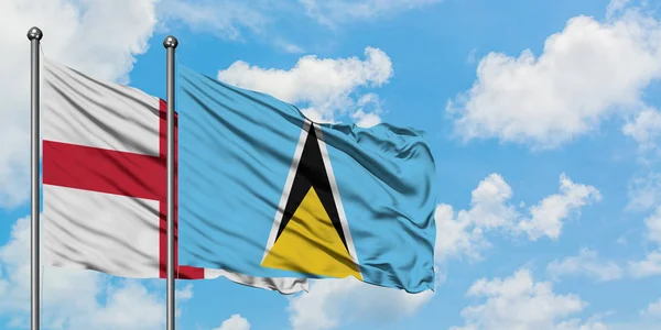 Engeland en Saint Lucia vlag zwaaien in de wind tegen witte bewolkte blauwe hemel samen. Diplomatie concept, internationale betrekkingen. — Stockfoto