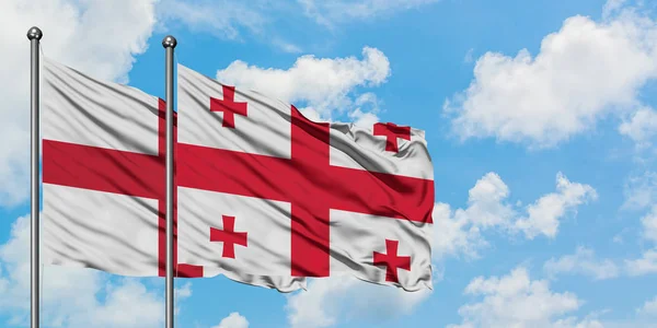 Bandera de Inglaterra y Georgia ondeando en el viento contra el cielo azul nublado blanco juntos. Concepto diplomático, relaciones internacionales . — Foto de Stock