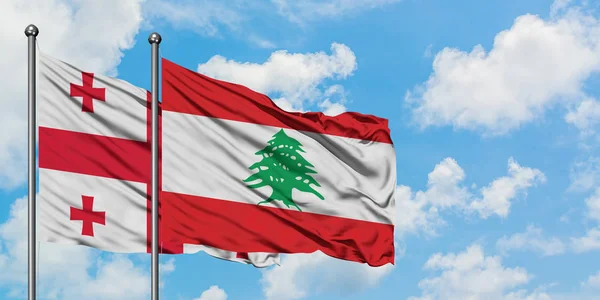 Bandera de Georgia y Líbano ondeando en el viento contra el cielo azul nublado blanco juntos. Concepto diplomático, relaciones internacionales . — Foto de Stock