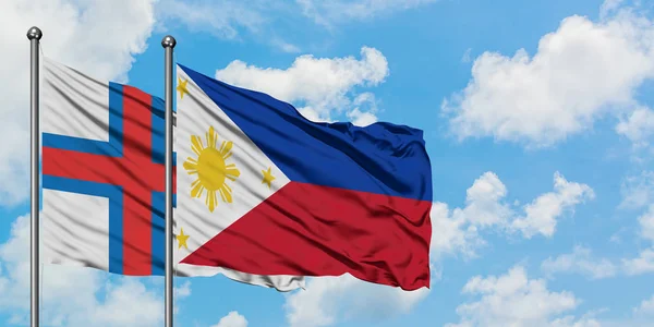 Bandera de las Islas Feroe y Filipinas ondeando en el viento contra el cielo azul nublado blanco juntos. Concepto diplomático, relaciones internacionales . — Foto de Stock