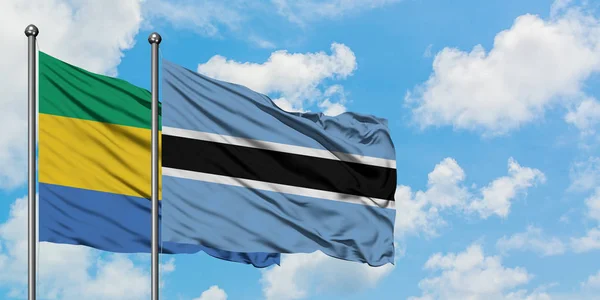 Gabon és Botswana zászló integetett a szél ellen, fehér felhős kék ég együtt. Diplomáciai koncepció, nemzetközi kapcsolatok. — Stock Fotó