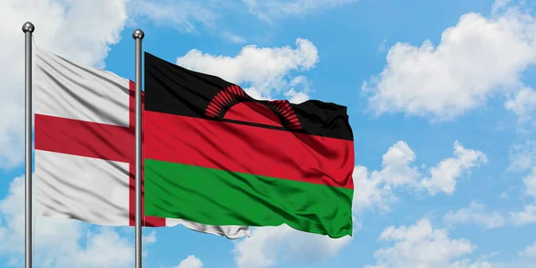 Bandera de Inglaterra y Malawi ondeando en el viento contra el cielo azul nublado blanco juntos. Concepto diplomático, relaciones internacionales . — Foto de Stock