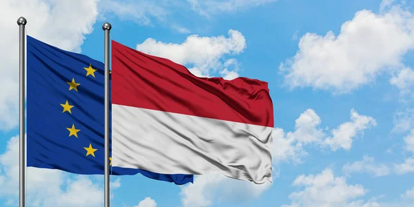 Bandera de la Unión Europea e Indonesia ondeando en el viento contra el cielo azul nublado blanco juntos. Concepto diplomático, relaciones internacionales . — Foto de Stock