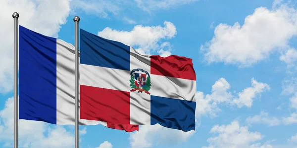 A bandeira da França e da República Dominicana agitando no vento contra o céu azul nublado branco juntos. Conceito de diplomacia, relações internacionais . — Fotografia de Stock