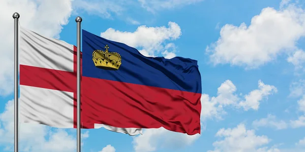 Bandera de Inglaterra y Liechtenstein ondeando en el viento contra el cielo azul nublado blanco juntos. Concepto diplomático, relaciones internacionales . — Foto de Stock